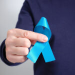 Homem segurando laço azul nas mãos, símbolo da campanha Novembro Azul de conscientização sobre a saúde do homem.